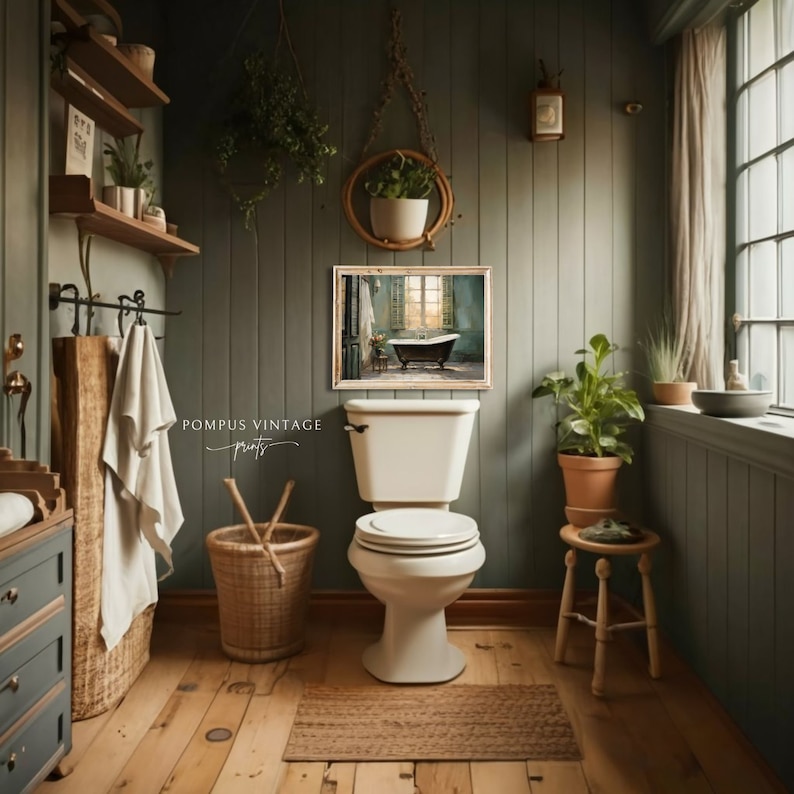 Peut inclure: Des toilettes blanches avec un couvercle ferm&eacute; dans une salle de bain aux murs verts et au sol en bois. Une estampe encadr&eacute;e d'une salle de bain vintage avec une baignoire est accroch&eacute;e au mur. Une plante en pot est pos&eacute;e sur un petit tabouret en bois.