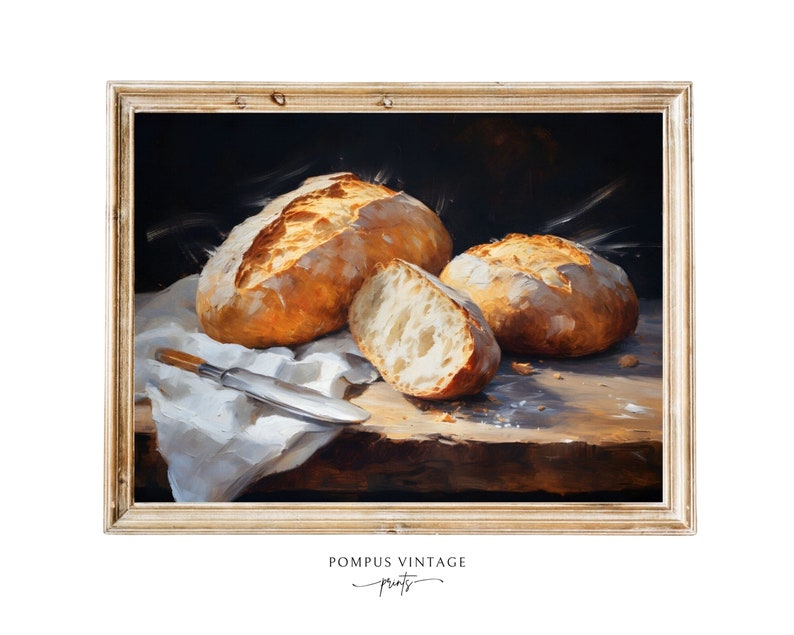 May include: A painting of three loaves of bread on a wooden table with a white cloth. The bread is golden brown and crusty. The painting is framed in a light wood frame.