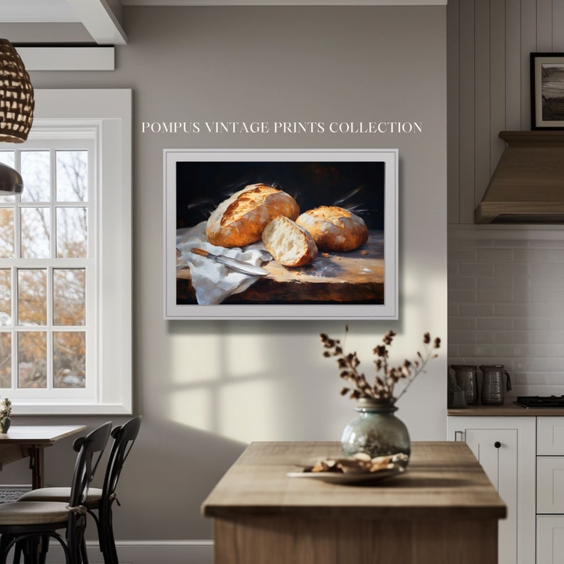 May include: A painting of three loaves of bread on a wooden table. The bread is golden brown and crusty. The painting is in a white frame.