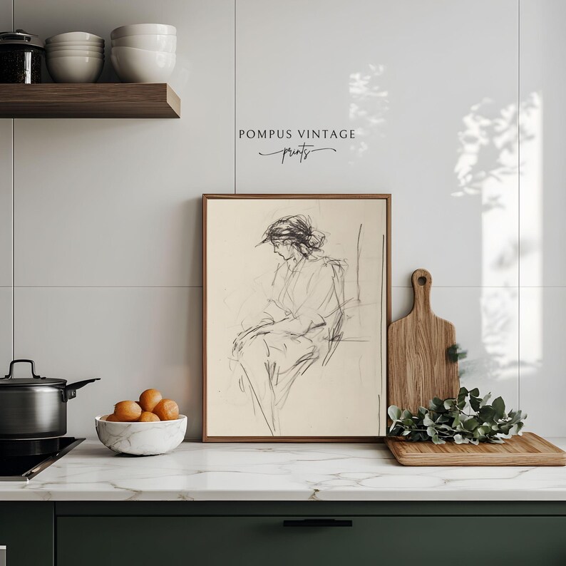 May include: A framed black and white line drawing of a woman sitting in a chair. The drawing is on a cream background and the frame is a light brown wood. The drawing is titled "Pompous Vintage Prints".