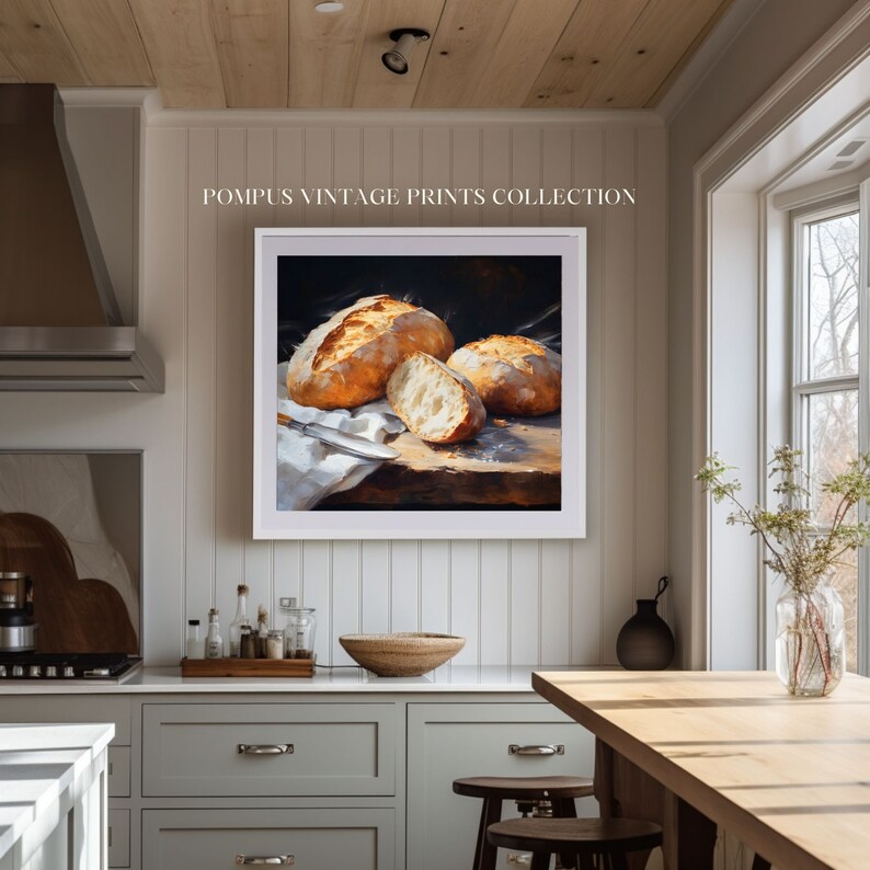 May include: A framed vintage print of a still life featuring three loaves of freshly baked bread on a wooden cutting board. The bread is golden brown and crusty, with a knife resting on the board. The print is set against a dark background and is framed in a white frame.