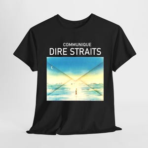 Puede incluir: Una camiseta negra de manga corta con el texto COMMUNIQUE DIRE STRAITS en letras blancas sobre un gráfico rectangular. El gráfico muestra una forma de sobre estilizada sobre un paisaje azul y amarillo con una pequeña figura sobre el agua.