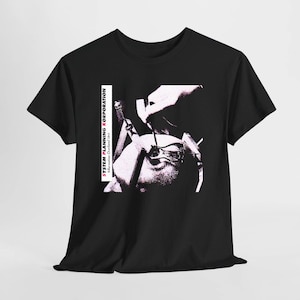 Puede incluir: Una camiseta negra de manga corta con un estampado gráfico blanco de alto contraste que muestra un procedimiento médico. El texto "SYSTEM PLANNING KORPORATION" y "Information Overload Unit" está impreso verticalmente en blanco y rosa a la izquierda.