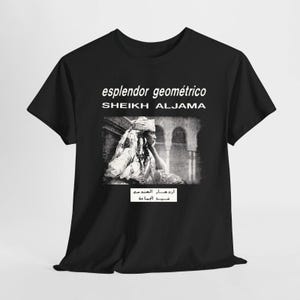 May include: A black short-sleeved t-shirt featuring the white text "esplendor geométrico" and "SHEIKH ALJAMA" above a black and white photographic print of a person in traditional attire, with additional Arabic text printed in a white rectangular box below.