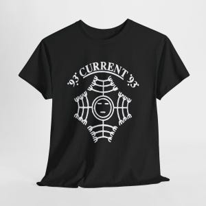 Puede incluir: Una camiseta negra de manga corta con un estampado gráfico blanco en el pecho. El diseño incluye el texto 'CURRENT 93' arqueado sobre un símbolo de cara circular central rodeado por cuatro patrones de líneas simétricas y ramificadas.