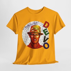 May include: A mustard yellow t-shirt featuring a circular graphic of a person wearing a hat. The text "Q: Are We Not Men?" is written above the head, and the word "DEVO" is printed vertically in red, green, black, and blue letters on the right side.