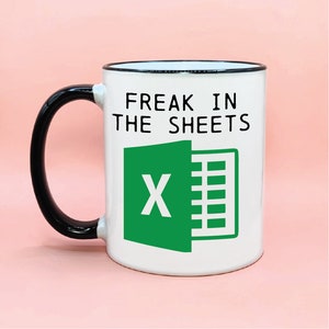 May include: White coffee mug with a black handle and black rim. The mug has a green Microsoft Excel logo and the text "Freak in the sheets".