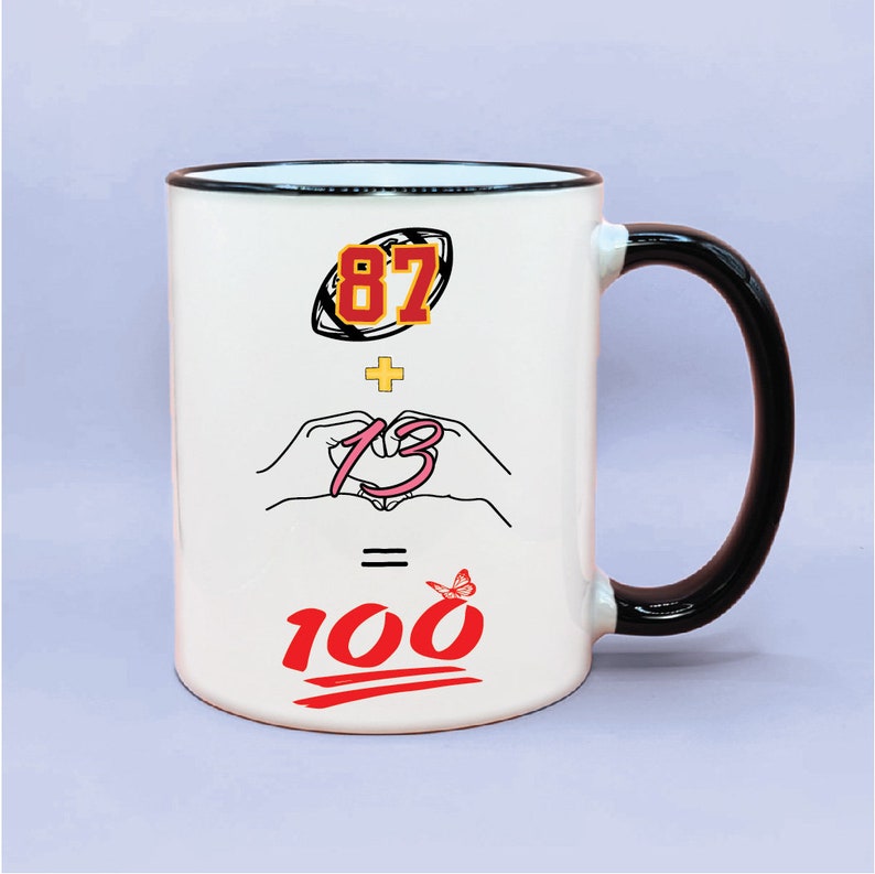 May include: White ceramic mug with a black handle. The mug has a graphic design with the numbers 87 and 13, a plus sign, an equals sign, and a butterfly. The numbers 100 are in red with a red squiggly line underneath.