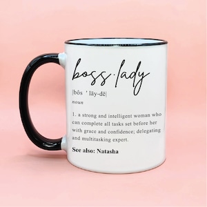 Puede incluir: Taza de cerámica blanca con asa y borde negros. La taza tiene un gráfico negro que dice "boss lady" con una definición debajo. La definición dice: "[bôs 'lāy-dē] sustantivo 1. una mujer fuerte e inteligente que puede completar todas las tareas que se le asignan con gracia y confianza; delegar y experta en multitarea. Ver también: Natasha"