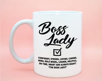 Pode incluir: Caneca de cerâmica branca com um design preto que diz "Boss Lady" com uma marca de verificação abaixo. O texto abaixo da marca de verificação diz "Confident, Strong, Loving, Caring, Hero, Role Model, Leader, Helpful, On Time, Smart and Always Right! "The Boss Lady!"