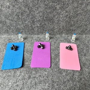 Könnte beinhalten: Drei Übungsmatten, eine blaue, eine lila und eine rosa, jede mit einem Satz schwarzer Hanteln darauf. Drei kleine Wasserflaschen sind im Hintergrund.