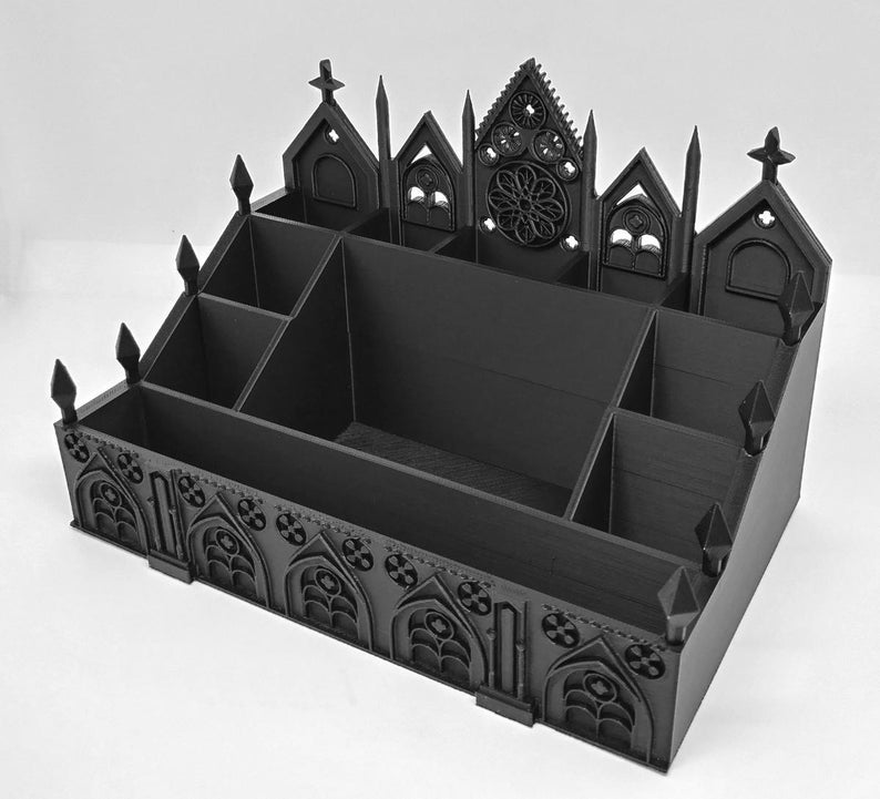 May include: A black desk organizer with a gothic cathedral design. The organizer has multiple compartments and is decorated with arched windows, crosses, and a rose window. The overall design is reminiscent of a church or cathedral.