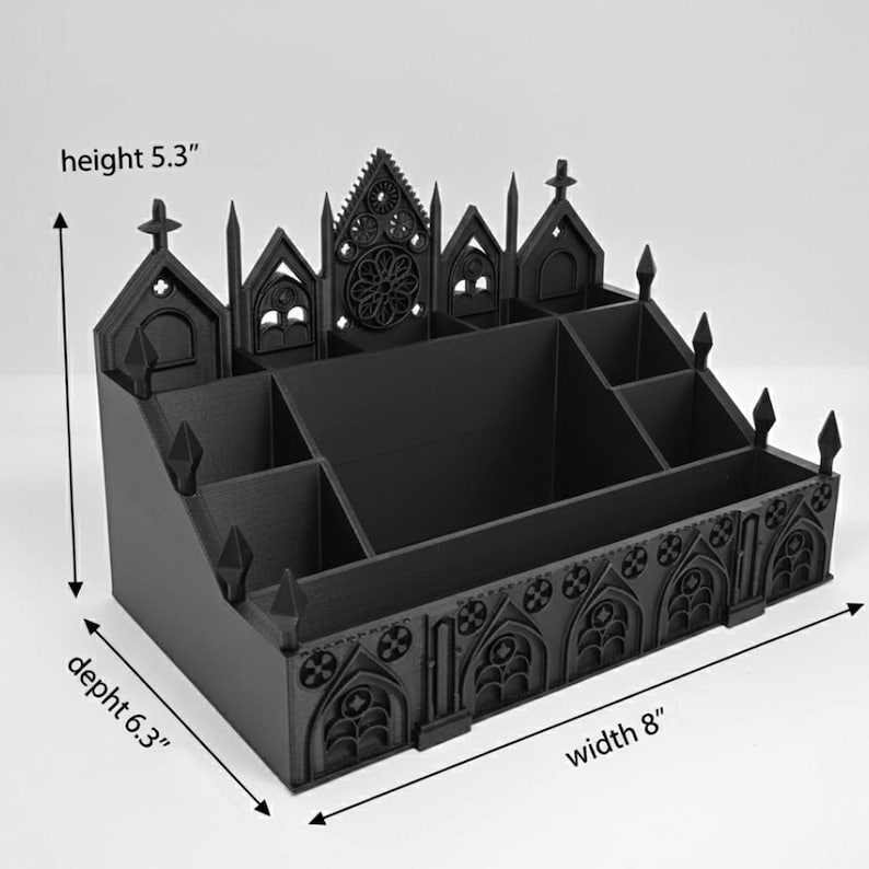 May include: Black desk organizer with a gothic cathedral design. The organizer is 8 inches wide, 6.3 inches deep, and 5.3 inches high. It features multiple compartments and decorative architectural details, including arched windows and crosses.