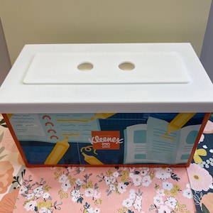 May include: White tissue box with a blue and orange design featuring a school theme. The box has a white lid with two holes for pulling out tissues. The box has the text "Kleenex 100 Count" on the front.