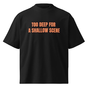 May include: Black t-shirt with a mock neck collar. The shirt features the orange text "TOO DEEP FOR A SHALLOW SCENE" across the chest. The shirt has short sleeves and a relaxed fit.