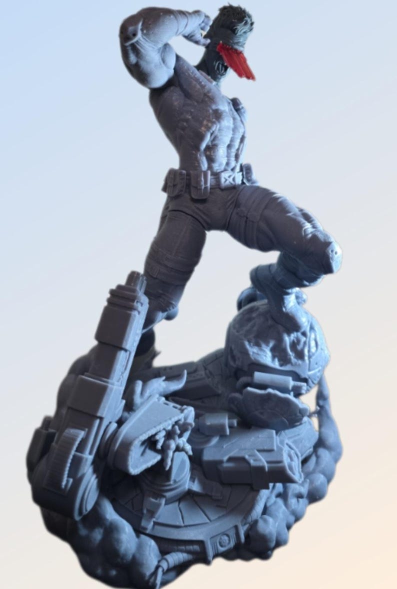 May include: A gray figurine of a muscular figure in a dynamic pose, wearing pants, a belt, and a red head covering. The figure is standing on a detailed base with mechanical elements. The overall design suggests a science fiction or action theme.