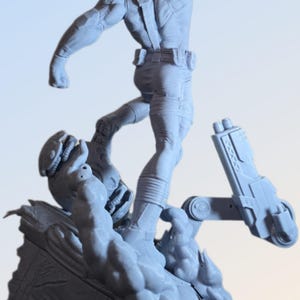 May include: A light gray action figure of a muscular character in a dynamic pose, with one arm raised. The figure is detailed with tactical gear and stands on a textured base with a futuristic weapon.