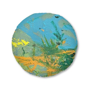 May include: A round, abstract painting with a textured surface. The artwork features a blue sky with green and yellow brushstrokes suggesting foliage and a golden-yellow foreground. The edges are a darker blue.