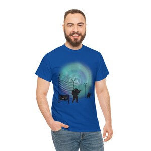 May include: Royal blue t-shirt featuring a graphic of soldiers behind a chain-link fence, with a colorful aurora borealis-like background. A sign reads "ONLY". The design is in black and white.