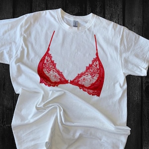 May include: White t-shirt with a red lace bra design printed on the front.