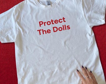 Protect The Dolls Baby Tee – Trans Rights Are Human Rights Shirt – LGBTQ+ Empowerment Pride Top