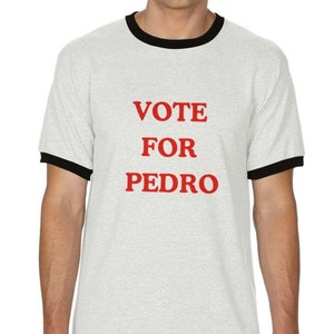 Könnte beinhalten: Ein weißes Ringel-T-Shirt mit schwarzem Besatz an Kragen und Ärmeln. Das Shirt zeigt den roten Text "VOTE FOR PEDRO" in einer fetten, serifenlosen Schrift. Das T-Shirt besteht aus einem weichen, hellen Material.