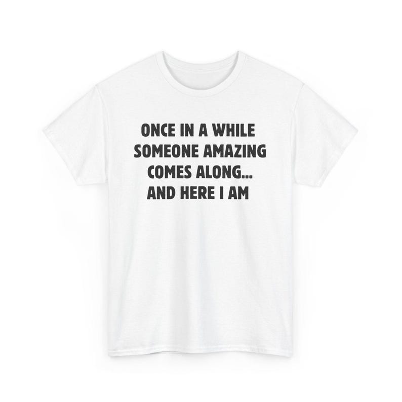 Op de afbeelding: Een wit t-shirt met de zwarte tekst: "ONCE IN A WHILE SOMEONE AMAZING COMES ALONG... AND HERE I AM". Het t-shirt heeft korte mouwen en is gemaakt van een zachte stof.
