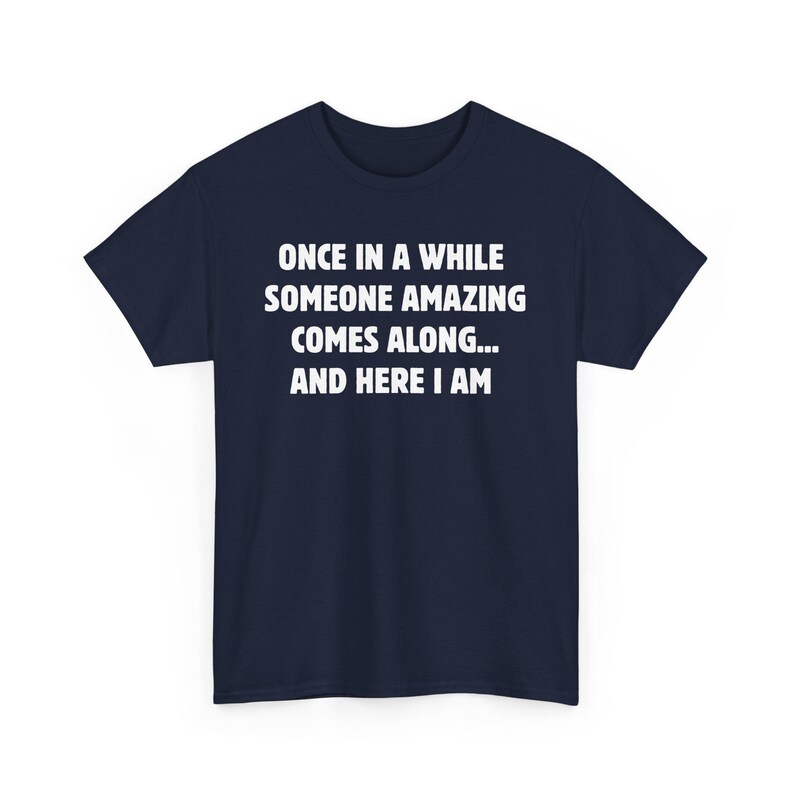 Op de afbeelding: Marineblauwe t-shirt met witte tekst: "ONCE IN A WHILE SOMEONE AMAZING COMES ALONG... AND HERE I AM." Dit t-shirt met korte mouwen en ronde hals is geschikt voor dagelijks gebruik.