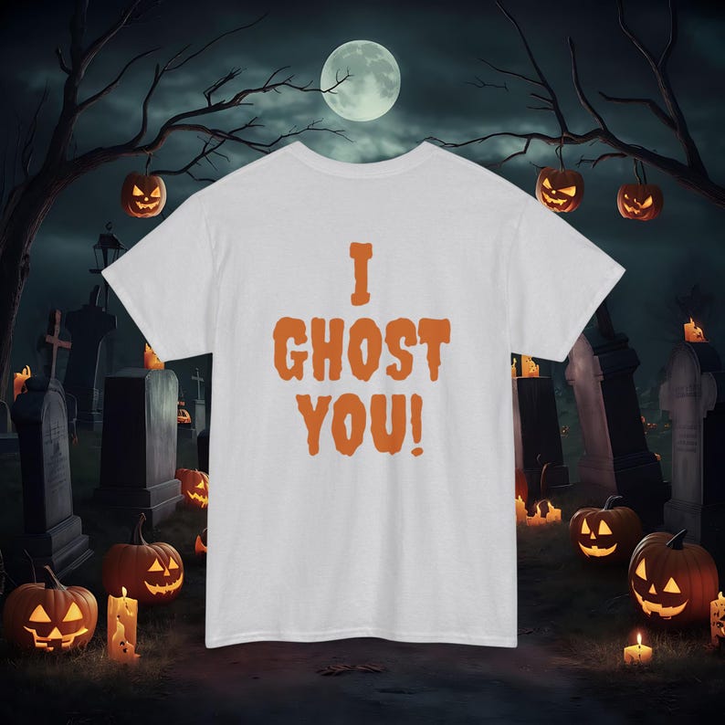 May include: White t-shirt with orange text that reads "I GHOST YOU!" against a backdrop of a spooky Halloween graveyard scene with jack-o-lanterns.