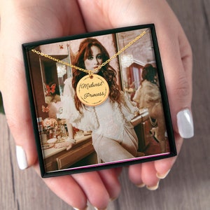 May include: A gold necklace with a round pendant that says "Midwest Princess" in cursive script. The necklace is in a black box with a picture of a woman wearing the necklace.