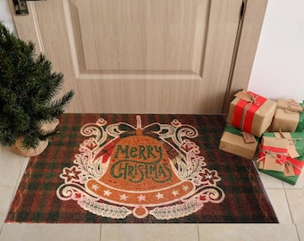 Puede incluir: Una alfombra de bienvenida roja, verde y marrón con un diseño de campana navideña. La campana tiene las palabras "Merry Christmas" escritas en ella.