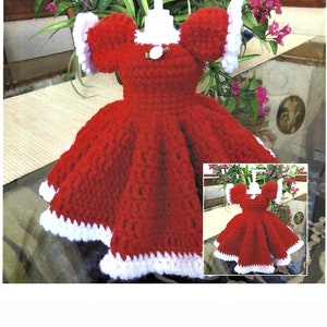 Puede incluir: Un vestido rojo de ganchillo con ribetes blancos, diseñado para adaptarse a una botella de dispensador de jabón. El vestido tiene un botón blanco y un cuello blanco de ganchillo.