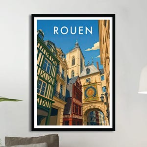 Può includere: Una stampa artistica incorniciata con un'illustrazione stilizzata di Rouen, Francia. L'opera raffigura una scena di strada con edifici colorati, tra cui una torre dell'orologio, sotto un cielo blu. La parola "ROUEN" è stampata in alto.