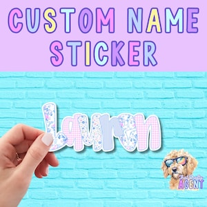 May include: A custom name sticker with the name "Lauren" in a playful font. The letters feature floral, gingham, and striped patterns. The background is a light blue brick wall with the text "CUSTOM NAME STICKER" above. A dog wearing sunglasses is in the corner.