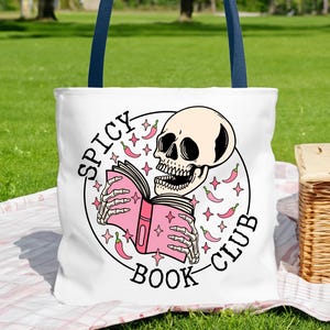 May include: White tote bag with a blue handle. The bag has a graphic of a skeleton reading a book with the text "Spicy Book Club" and chili peppers around the skeleton.