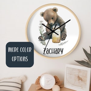 May include: A round wooden clock with a white face featuring a watercolor illustration of a brown bear holding a jar of honey. The clock has black hands and the name "Zachary" is printed below the bear.