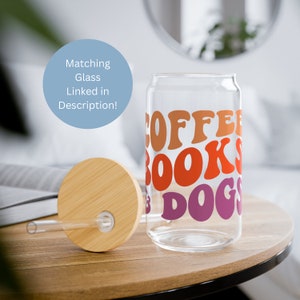May include: A glass can with a bamboo lid and a straw. The can has the words "Coffee, Books, & Dogs" printed on it in a retro font with orange, red, and purple colors.
