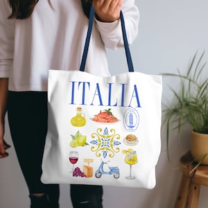 K&ouml;nnte beinhalten: Wei&szlig;e Tragetasche mit blauen Henkeln. Das Wort "ITALIA" ist in Blau aufgedruckt. Die Tasche zeigt Aquarellillustrationen italienischer Speisen und Sehensw&uuml;rdigkeiten, darunter Pasta, Zitronen und einen Roller. Die Tasche wird von einer Person gehalten.