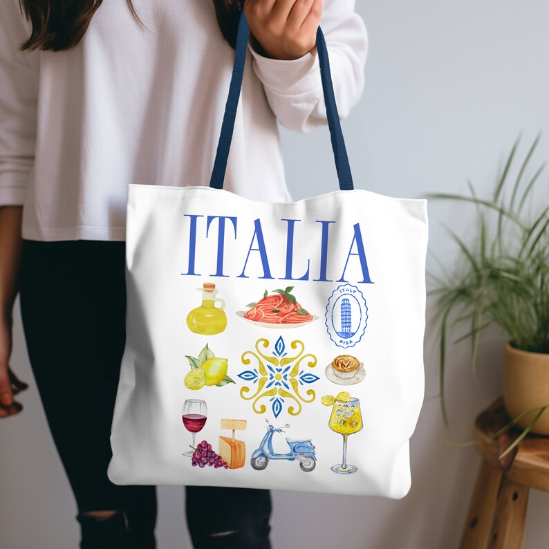 K&ouml;nnte beinhalten: Wei&szlig;e Tragetasche mit blauen Henkeln. Das Wort "ITALIA" ist in Blau aufgedruckt. Die Tasche zeigt Aquarellillustrationen italienischer Speisen und Sehensw&uuml;rdigkeiten, darunter Pasta, Zitronen und einen Roller. Die Tasche wird von einer Person gehalten.