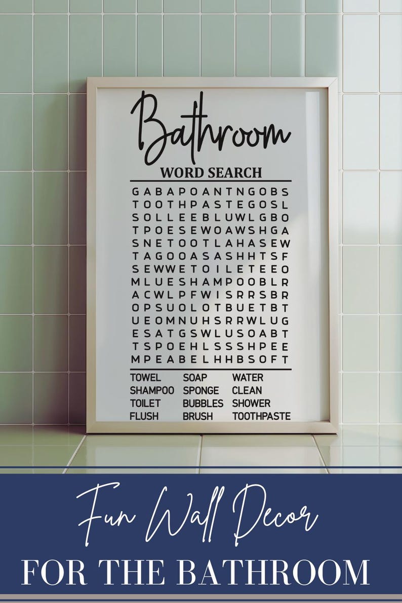 May include: A white framed print with a black and white word search puzzle titled "Bathroom Word Search". The puzzle includes words related to bathroom items such as "towel", "soap", "water", "shampoo", "sponge", "clean", "toilet", "bubbles", "shower", "flush", "brush", and "toothpaste". The print also includes the text "Fun Wall Decor for the Bathroom".