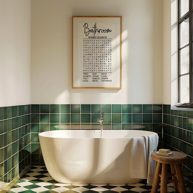 May include: A white bathroom with green tile and a white bathtub. A framed print with the word "Bathroom" and a word search puzzle is hanging on the wall. The word search puzzle includes words like "towel", "soap", "water", "shampoo", "sponge", "clean", "toilet", "bubbles", "shower", "flush", "brush", and "toothpaste".