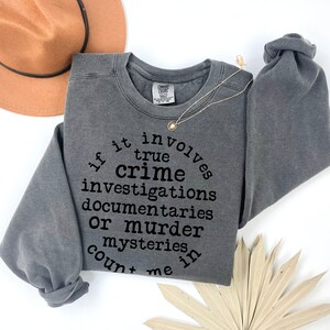 May include: Gray sweatshirt with the text "If it involves true crime investigations, documentaries or murder mysteries, count me in."