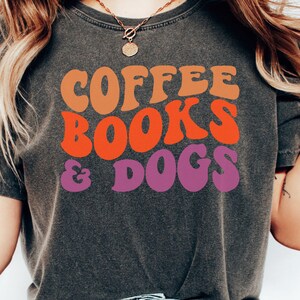 May include: A gray t-shirt with the text "COFFEE BOOKS & DOGS" in a retro font with orange, red, and purple colors.