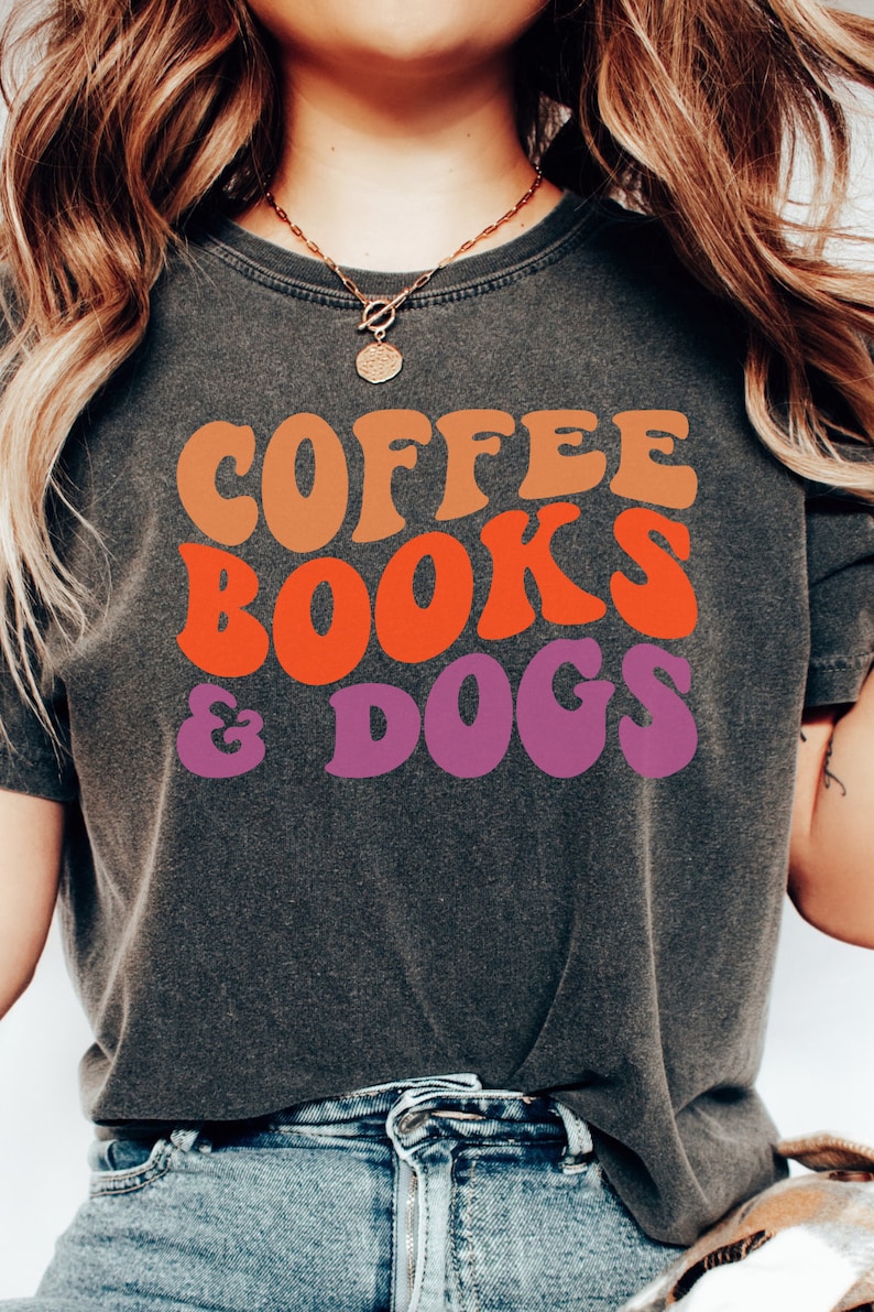 May include: A gray t-shirt with the text "COFFEE BOOKS & DOGS" in a retro font with orange, red, and purple colors.