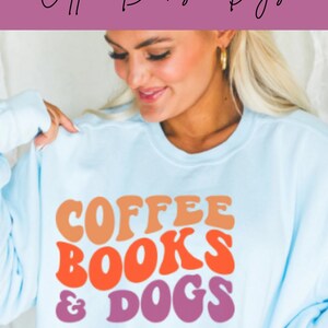May include: A light blue sweatshirt with the text "COFFEE BOOKS & DOGS" in a retro font. The text is in shades of orange, red, and purple.