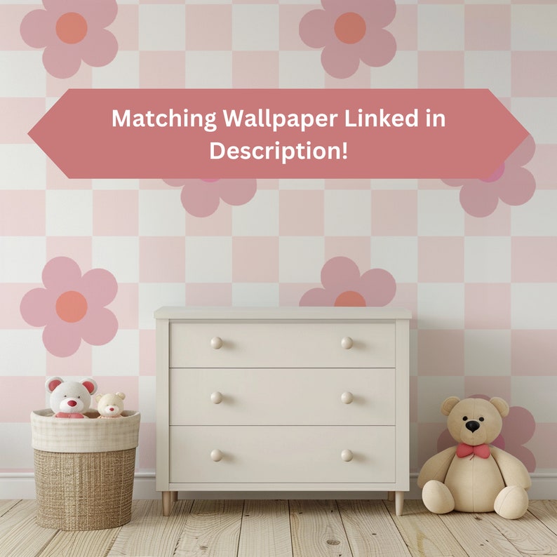 K&ouml;nnte beinhalten: Eine wei&szlig;e Kommode mit drei Schubladen vor einer pinkfarbenen und wei&szlig;en karierten Wand mit pinkfarbenen Blumenaufklebern. Der Text "Matching Wallpaper Linked in Description!" befindet sich auf einem pinkfarbenen Pfeil &uuml;ber der Kommode. Zwei Teddyb&auml;ren stehen auf dem Boden vor der Kommode.