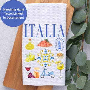 K&ouml;nnte beinhalten: Wei&szlig;es Waffel-K&uuml;chentuch mit dem Wort "ITALIA" in Blau. Das Handtuch zeigt Aquarellillustrationen italienischer Speisen und Sehensw&uuml;rdigkeiten, darunter Pasta, Zitronen und einen Roller. Ein blauer Kreis oben links sagt "Passendes Handtuch in der Beschreibung verlinkt!"