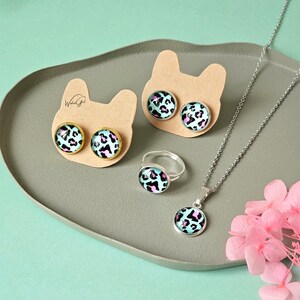 Könnte beinhalten: Ein Schmuckset mit einem türkisblauen und schwarzen Leopardenmuster. Das Set enthält eine Halskette, einen Ring und ein Paar Ohrringe.