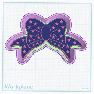 May include: A layered bow-shaped object in shades of purple, blue, and green. The center layer is dark blue with pink star patterns. The object is on a grid background with the word "Workplane" and the word "Inches" in the bottom corners.