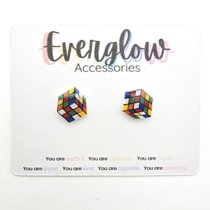 May include: A pair of Rubik's Cube stud earrings on a white card. The card features the text "Everglow Accessories" and motivational phrases. The earrings are square-shaped with red, blue, green, yellow, orange, and white squares.